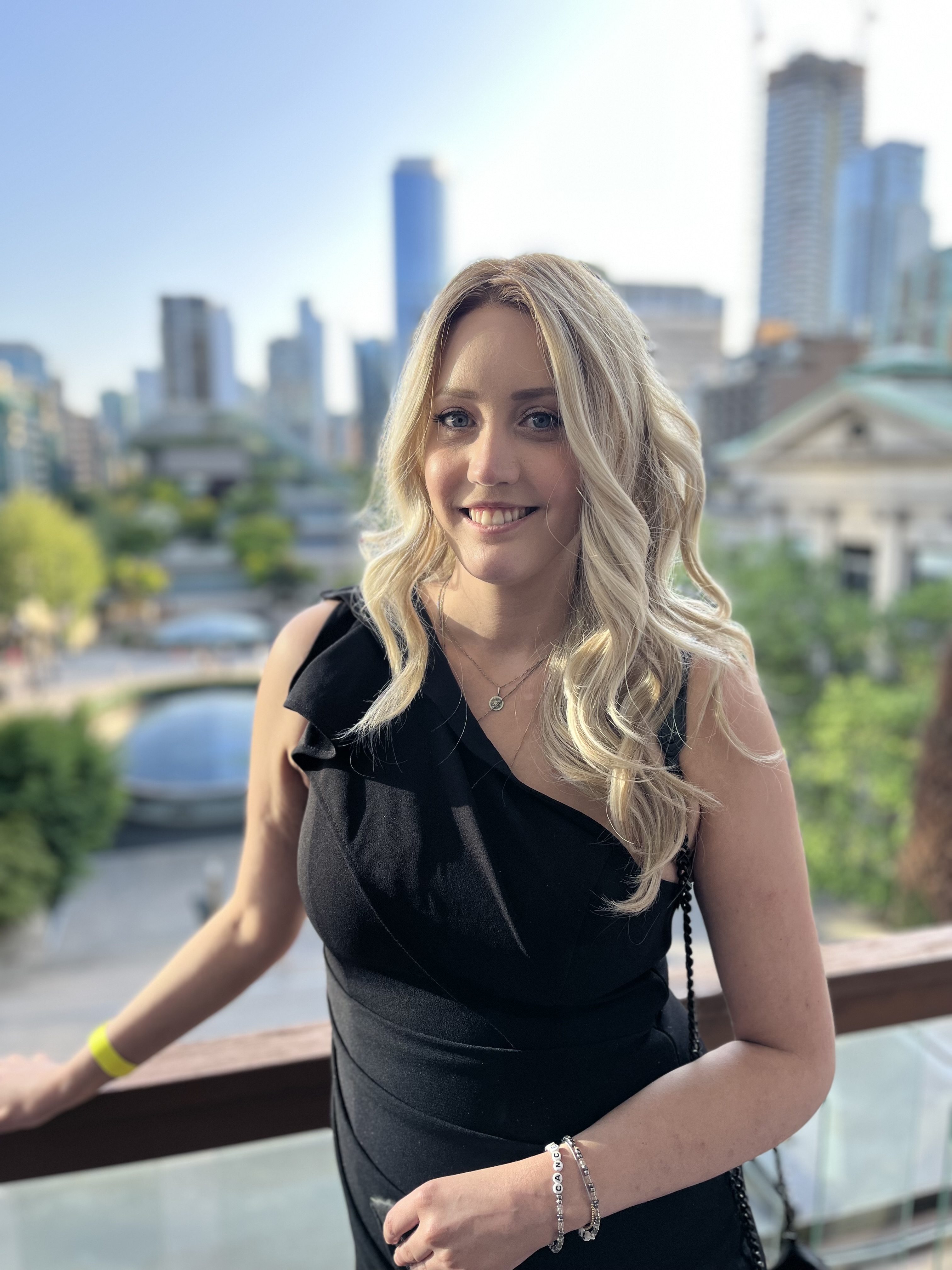 Ashley s'appuie sur une balustrade avec une vue pittoresque sur la ville derrière elle.