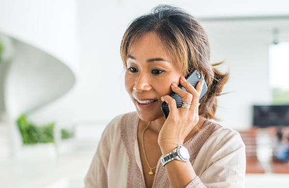 Une femme devant un arrière-plan flou et lumineux, parlant sur son téléphone.