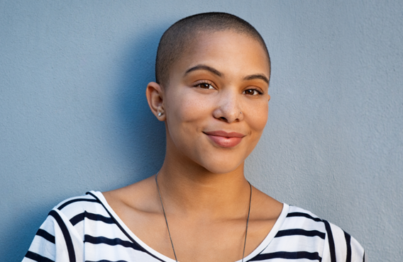 Femme debout contre un mur en souriant.