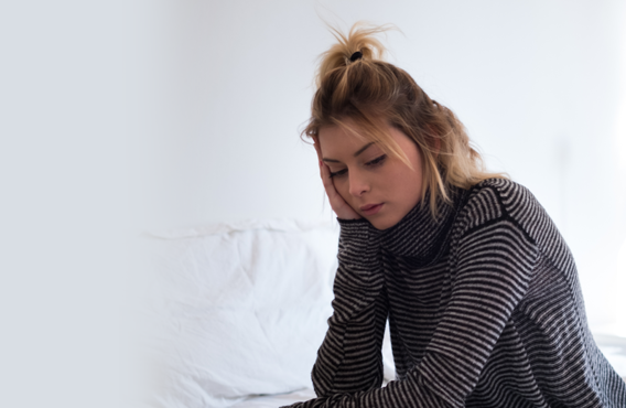 Une jeune femme assise sur son lit regardant quelque chose.