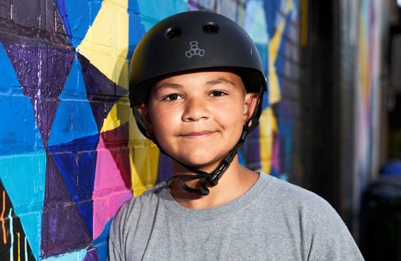 Un garçon nommé Justin avec un casque debout à côté d'un mur coloré.