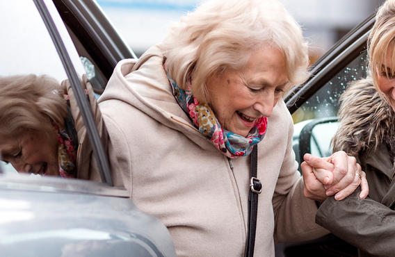 Une femme aidant une vieille femme à sortir d'un véhicule