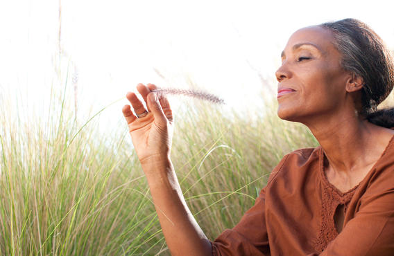 A woman holding a feather outside touching long grass