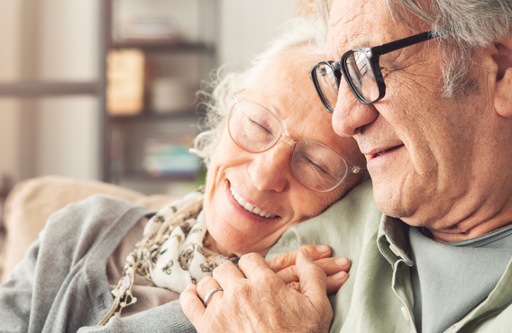 An older man and woman embrace on a couch