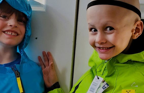 Deux enfants en vestes colorées se tiennent près d'une porte, avec l'inscription « DON X4 » et le texte de la campagne de la Société de leucémie et lymphome du Canada à droite.