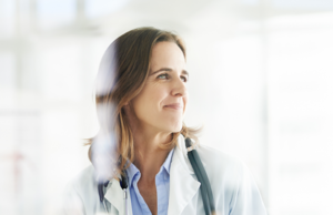 Une femme médecin souriant tout en regardant au loin.