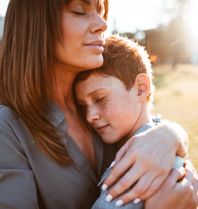 Mère étreignant son fils à l'extérieur par une journée ensoleillée