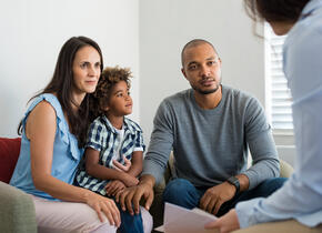 Une famille de 3 personnes (père, mère et fils) se faisant annoncer une nouvelle par une personne hors de vue.