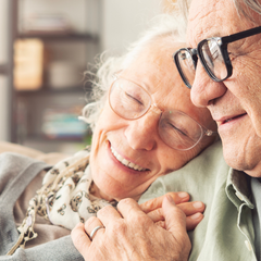 An older man and woman embrace on a couch
