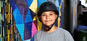 Un garçon nommé Justin avec un casque debout à côté d'un mur coloré.